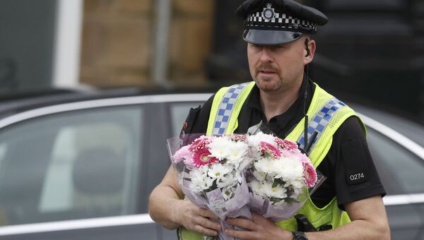 Полицейский несет цветы к месту убийства депутата Джо Кокс в Бирсталле близ Лидса