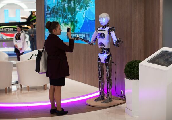 Девушка фотографирует робот Теспиан на выставке SPIEF Investment & Business Expo