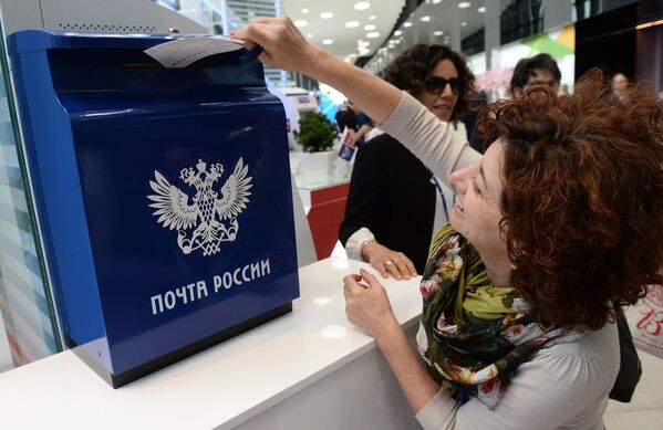 Посетительница XX Петербургского международного экономического форума опускает открытку в ящик Почты России