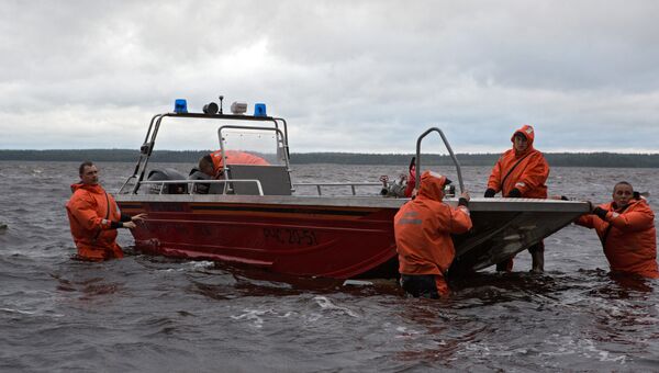 Спасатели спускают лодку на воду на месте проведения поисково-спасательной операции в районе озера Сямозеро в Карелии