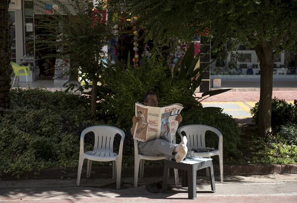 Мужчина читает газету на улице курорта Кемер в Турции