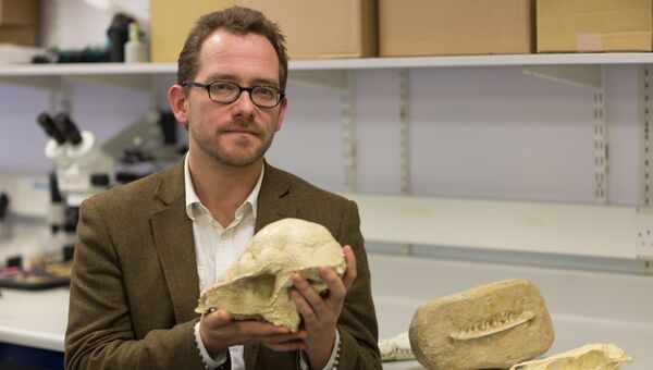 Николас Лонгрич держит череп древнего животного