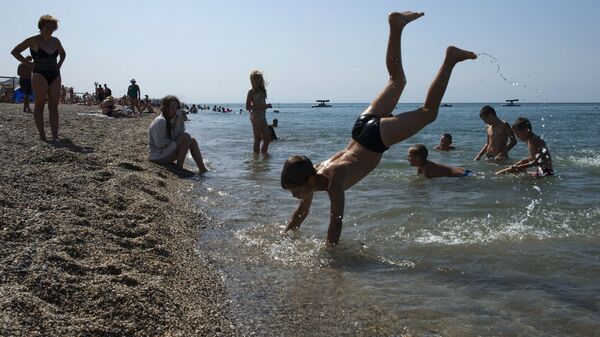 Отдыхающие на пляже Черного моря у детского оздоровительного лагеря Голубая волна в Сакском районе Крыма