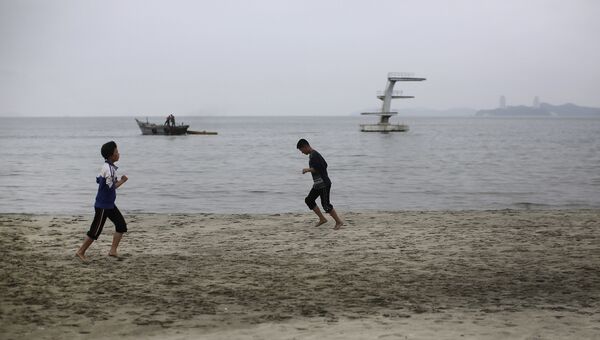 Молодые люди бегают трусцой по пляжу в Северной Корее. 21 июня 2016