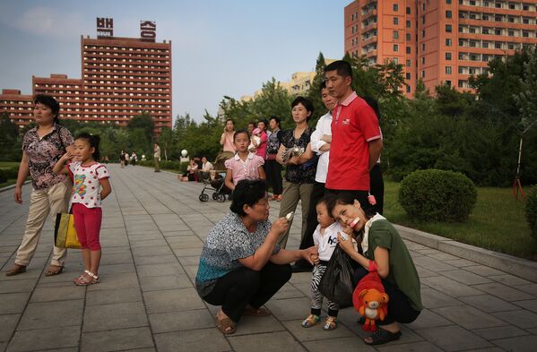 Люди наблюдают за массовым танцем членов партий в Пхенеьяне, Северная Корея