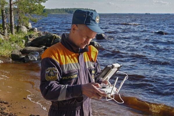 Сотрудник МЧС России обследует береговую линию при помощи беспилотного летательного аппарата во время поисково-спасательных работ на озере Сямозеро в Карелии