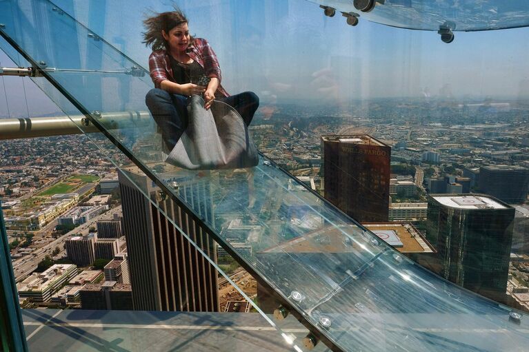 Женщина скользит вниз по Skyslide на внешней стороне Bank Tower в Лос-Анджелесе, США. Июнь 2016