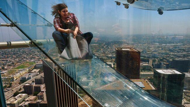 Женщина скользит вниз по Skyslide на внешней стороне Bank Tower в Лос-Анджелесе, США. Июнь 2016