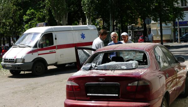 Мужчины у автомобиля, пострадавшего в результате взрыва на территории республиканского травматологического центра в Донецке