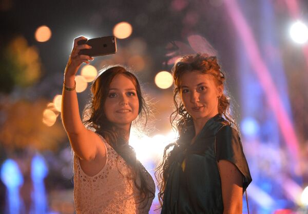 Выпускники московских школ фотографируются на мобильный телефон во время празднования Последнего звонка
