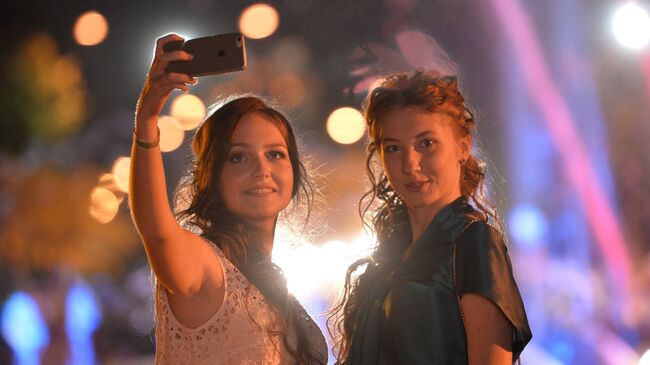 Выпускники московских школ фотографируются на мобильный телефон во время празднования Последнего звонка