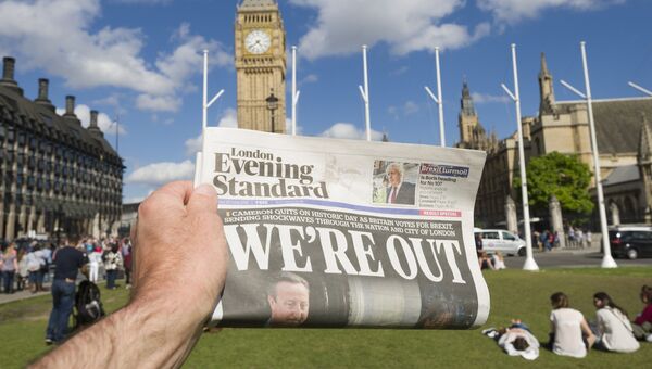 Мужчина держит в руке газету у здания парламента в Лондоне. Июнь 2016 года