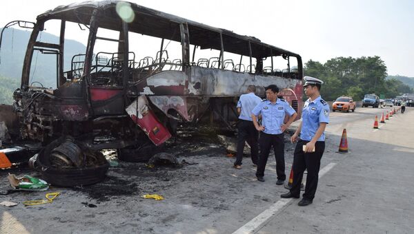 Полицейские рядом со сгоревшим автобусом в китайской провинции Хунань. 26 июня 2016 года