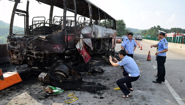 Полицейские рядом со сгоревшим автобусом в китайской провинции Хунань. 26 июня 2016