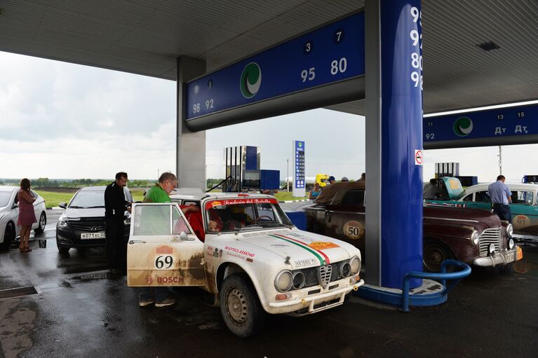 Участник на автомобиле Alfa Romeo Giulietta TI (1969 г.) на этапе гонки международного ретро-ралли Пекин - Париж-2016 во время дозаправки топливом в Алтайском крае