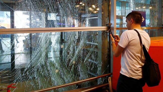 Человек фотографирует разбитые в результате теракта стекла в аэропорту Ататюрк. Стамбул, 29 июня 2016