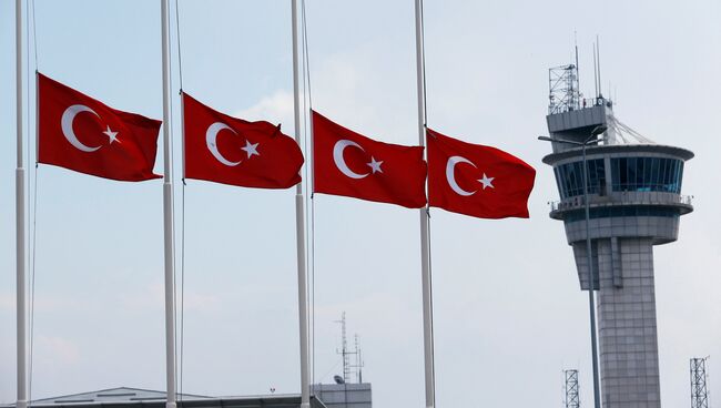 Приспущенные турецкие флаги на фоне вышки в аэропорту имени Ататюрка в Стамбуле, Турция. 29 июня 2016