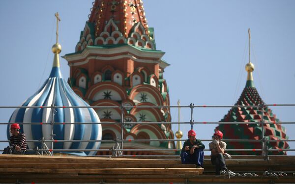 Рабочие отдыхают на строительных лесах на фоне Покровского собора на Красной площади