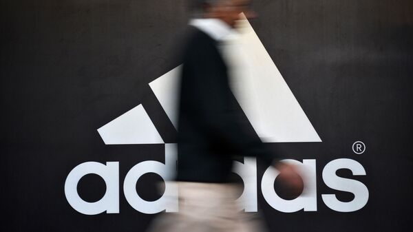 Человек проходит мимо логотипа Adidas