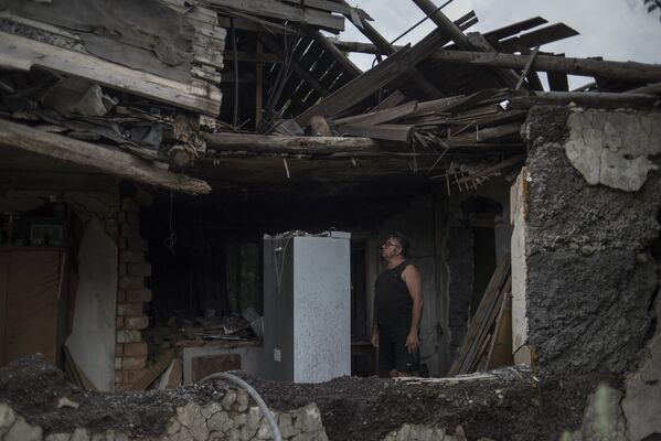 Местный житель в своем доме, разрушенном в результате обстрела