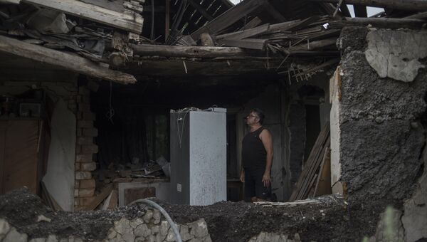 Местный житель в своем доме, разрушенном в результате обстрела. Архивное фото