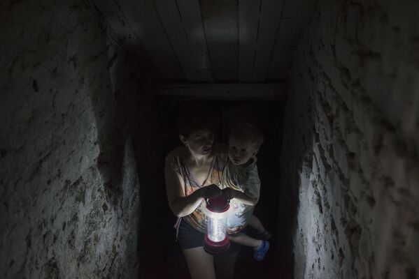 Женщина с ребенком прячется в подвале своего дома в Горловке