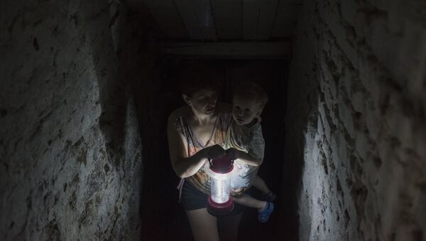 Женщина с ребенком прячется в подвале своего дома в Горловке