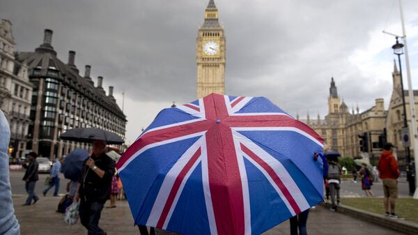 Человек с зонтом с флагом Великобритании у Биг Бена и здания парламента в Лондоне.Архивное фото