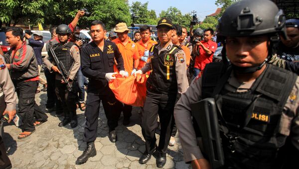 Полицейские выносят тело террориста-смертника с места нападения на полицейский участок в Индонезии. 5 июля 2016