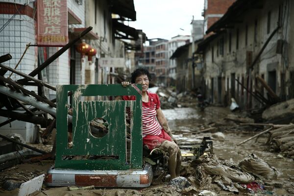 Женщина сидит на руинах после тайфуна Непартак в Китае