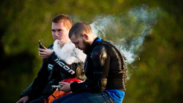 Молодые люди курят электронные сигареты на смотровой площадке Воробьевых гор в Москве. Архивное фото