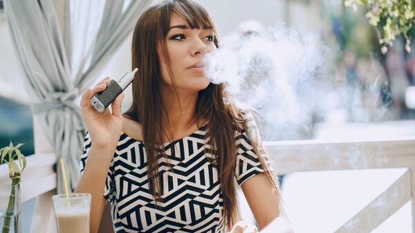 Девушка с электронной сигаретой в кафе
