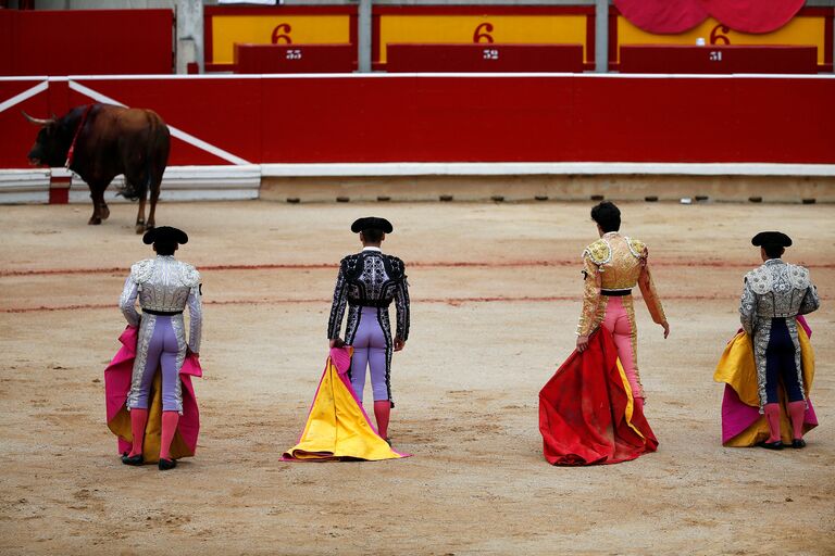 Испанские тореадоры наблюдают за умирающим быком во время фестиваля Сан-Фермин в Испании. 2016 год