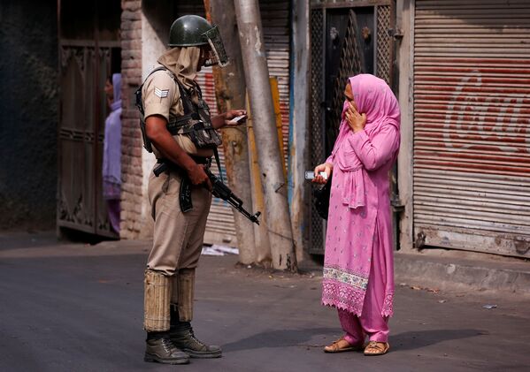 Индийский полицейский проверяет удостоверение личности женщины во время комендантского часа в Шринагаре 14 июля 2016 год