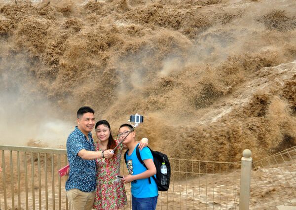 Люди фотографируются перед водопадом Хукоу, Китай