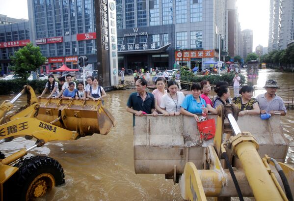 Люди добираются на работу в ковшах экскаваторов. Наводнения в Ухане, Китай