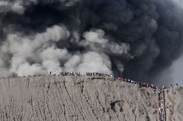 Люди на краю кратера вулкана Бромо в Индонезии. Июль 2016