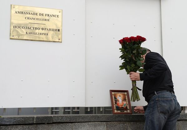 Мужчина возлагает цветы к посольству Франции в Москве в память о погибших в результате террористических акта в Ницце