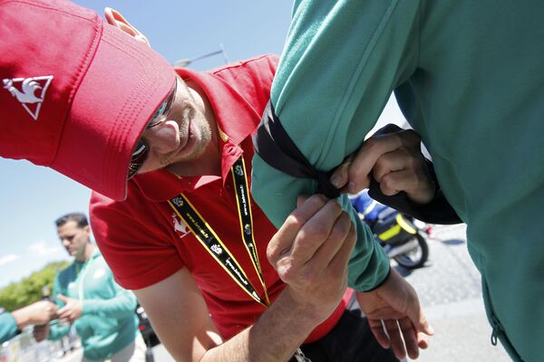 Участник Тур де Франс повязывает черную ленту на руку в память о жертвах теракта в Ницце