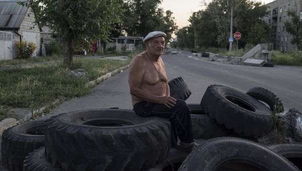 Мужчина сидит на покрышках на одной из улиц в поселке Веселое Донецкой области. Архивное фото