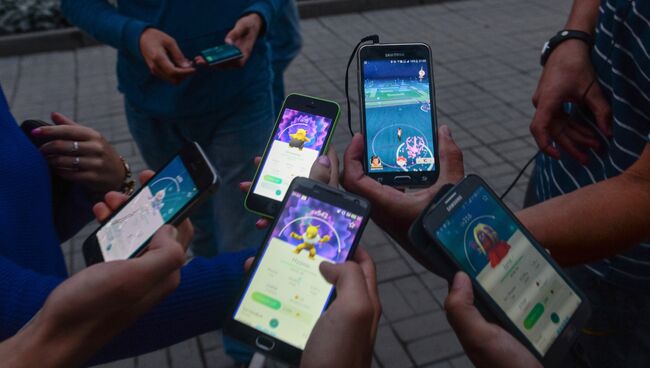 Молодежь в парке перед Новосибирским театром оперы и балета играет в Pokemon Go