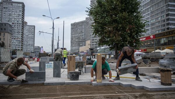 Рабочие укладывают плитку во время реконструкции улицы Новый Арбат в Москве