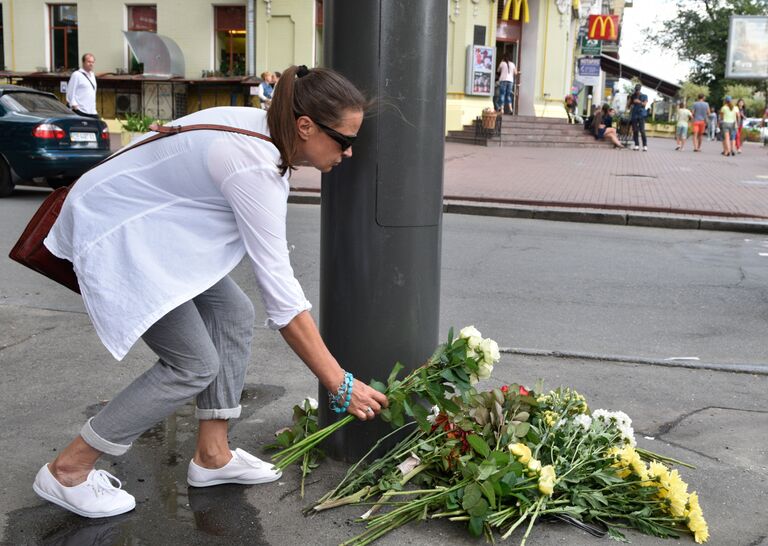 Женщина возлагает цветы к месту гибели журналиста Павла Шеремета