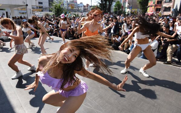 Танцоры в бикини выступают во время флешмоба на площади перед станцией Синдзюку в Токио