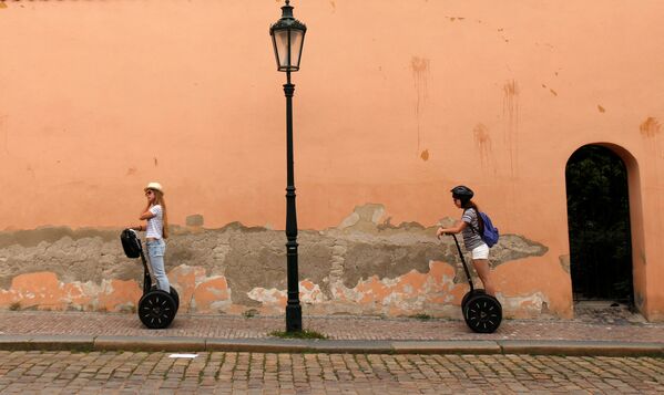 Туристы едут по улице Праги на сегвеях