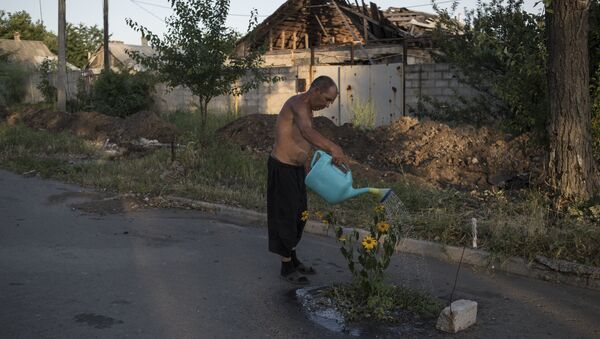 Мужчина поливает цветы на одной из улиц поселка Веселое Донецкой области. Архивное фото