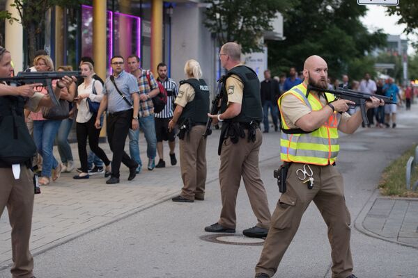 Полиция сопровождает людей, покидающих здание торгового центра, где неизвестные открыли стрельбу