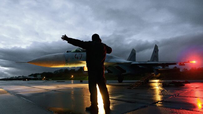 Военный техник дает отмашку на взлет истребителя Су-27. Архивное фото