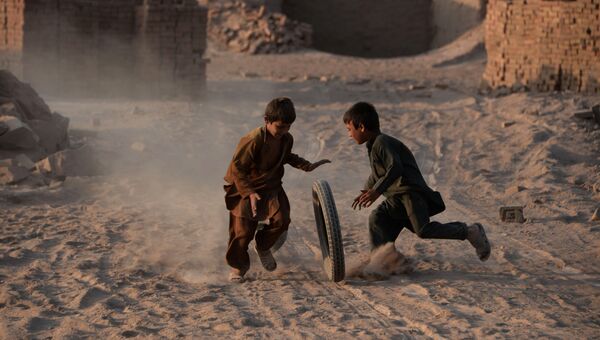 Дети играют с шиной на пыльной дороге на окраине Джелалабада. Архивное фото