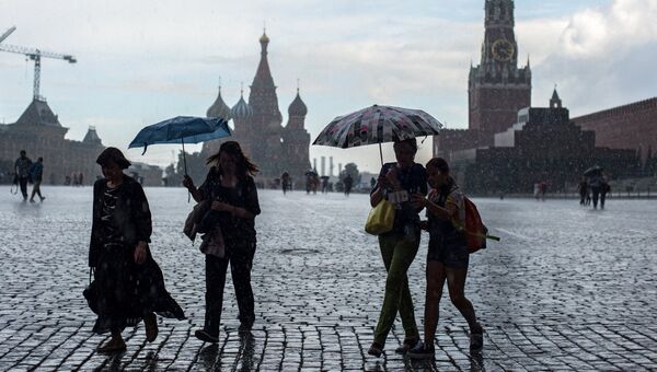 Горожане во время дождя на Красной площади в Москве